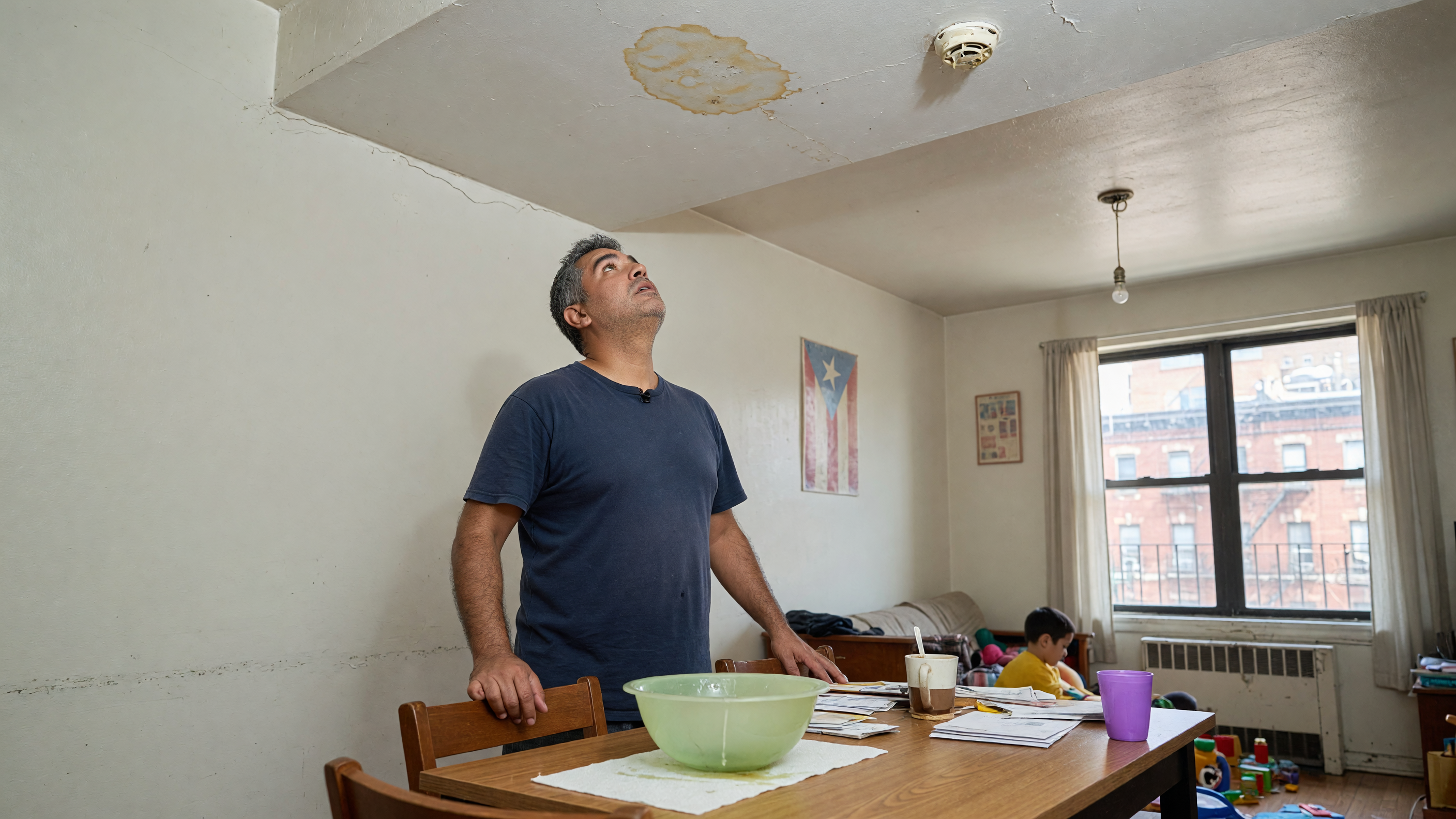 A father looks up at a small ceiling stain.